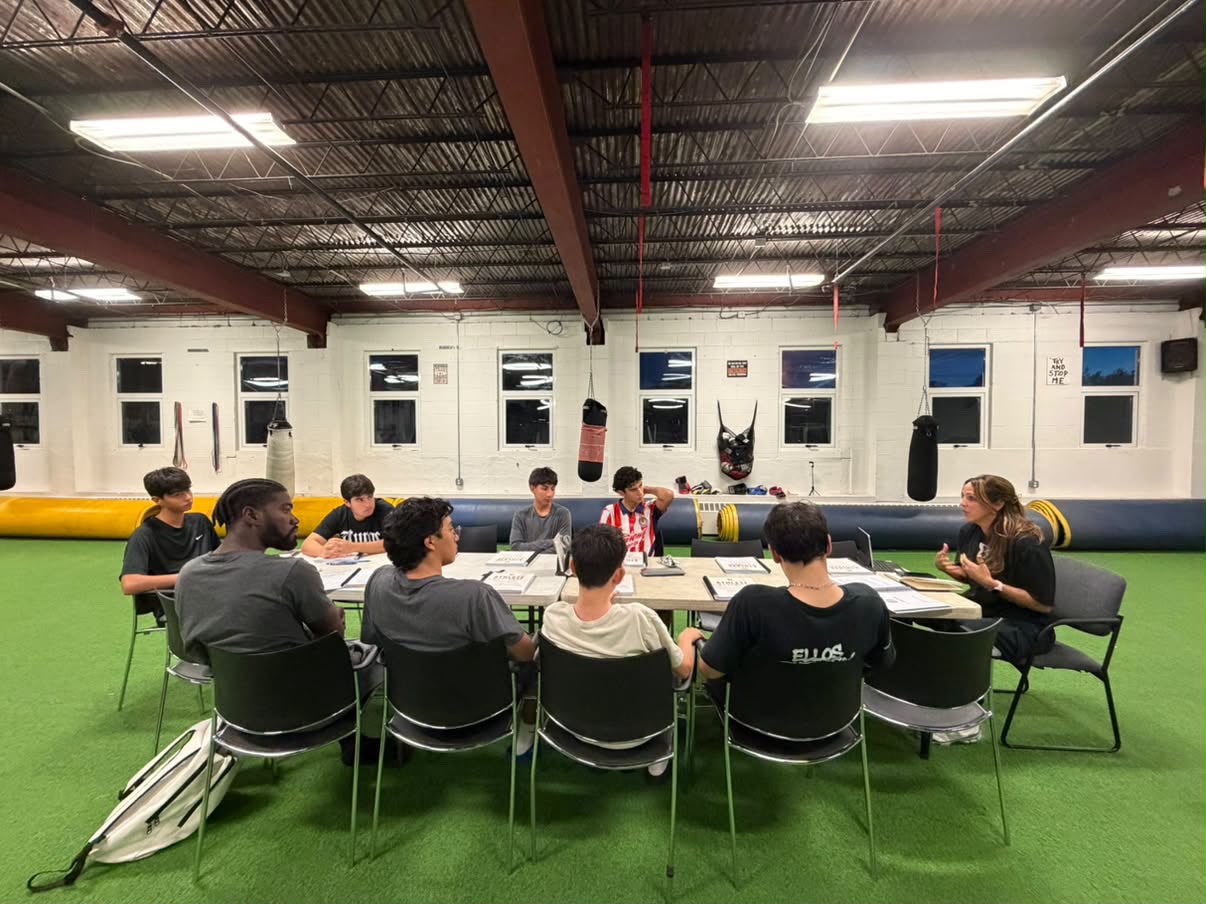 A BrioForm team session in progress, athletes working through the Athlete Standard workbook together around one table